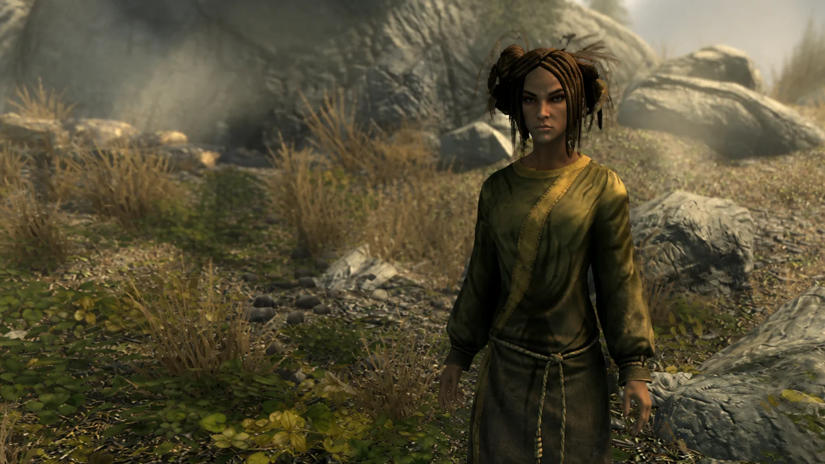 A mature Bosmer druid standing among low plants and weathered rocks in an evergreen grove