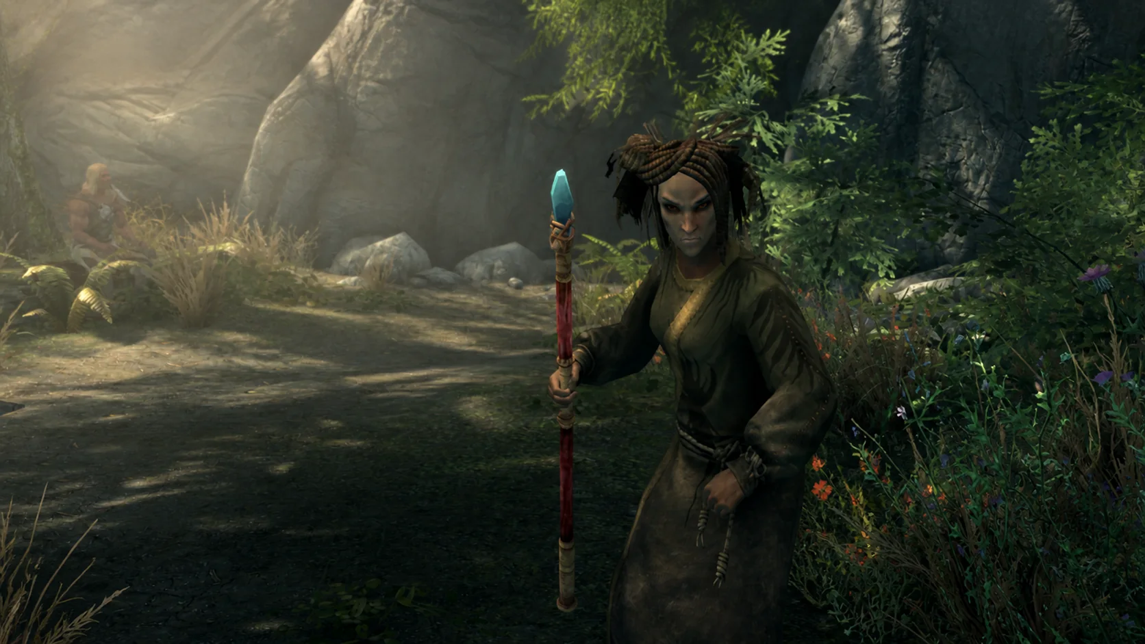 The mature Wildspeaker raising a crystal-tipped staff among the flowers and sunlit stone of Moss Mother Cavern